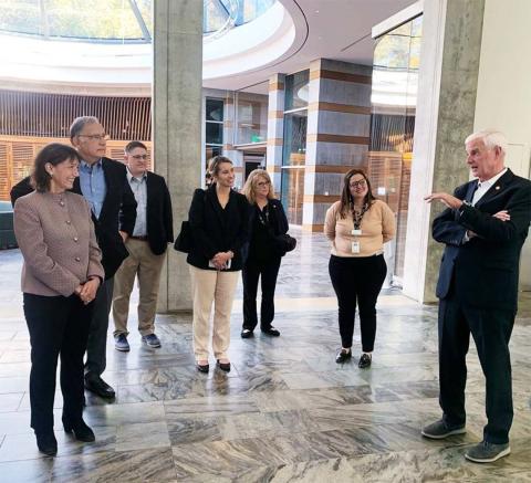 Dr. Bertagnolli, flanked by a senator, congressman and staffers, stand in large, bright building under skylight dome.