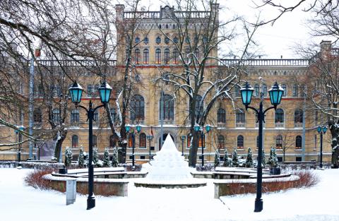 A large university building with snow-covered fountain in front