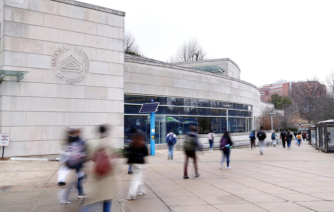 Employees walk past NIH Gateway