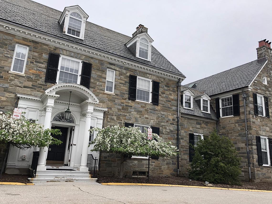 Crab apples trees in front of a two-story stone house