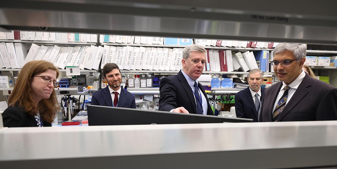 Scientists gather with Bhattacharya, with view taken between lab shelves