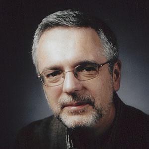 Headshot of Dr. Camerini-Otero. He is gray-haired and is wearing glasses and a black shirt.