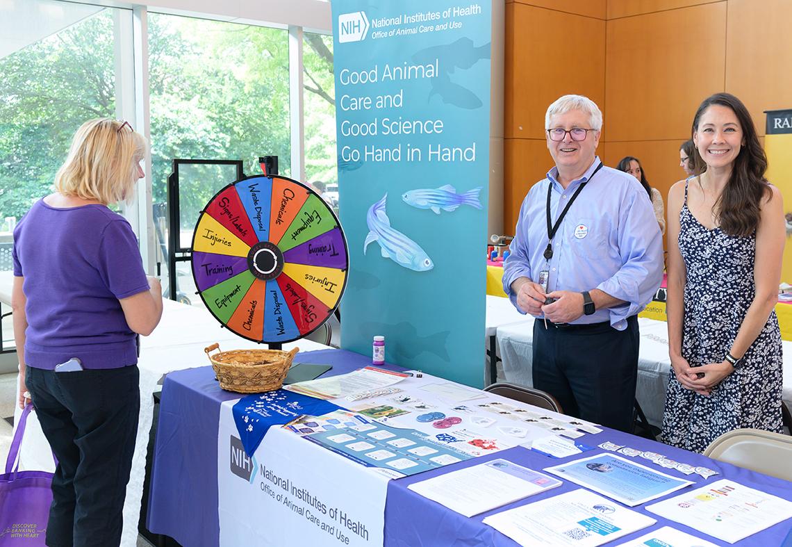 Woman spins colorful wheel at education game at info table in the lobby