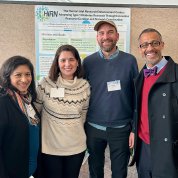 Four individuals pose in front of a scientific poster.