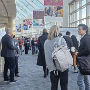 A crowd of people gather around scientific posters in a brightly lit atrium.